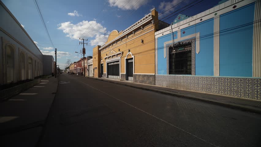 Slow motion push in down a deserted street showing colorful buildings in Mexico, Merida, Yucatan in early evening.