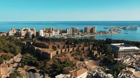 Malaga city Roman theatre and port area views in Andalusia, Spain. With  yachts docked in the harbour and high-rise buildings towering over the palm tree-lined promenade.