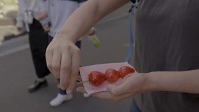 This video shows a caucasian woman eating a skewer of Ichigo ame candied strawberry treats in the streets of Japan.