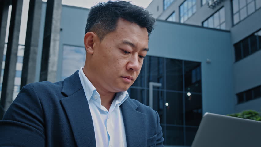 Serious manager boss leader company CEO busy with online project startup analyze data in internet corporate app Korean Chinese 40s middle-aged businessman employer entrepreneur man work with laptop | Shutterstock HD Video #1098022563