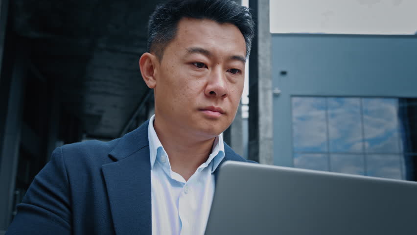 Serious manager boss leader company CEO busy with online project startup analyze data in internet corporate app Korean Chinese 40s middle-aged businessman employer entrepreneur man work with laptop | Shutterstock HD Video #1098022563