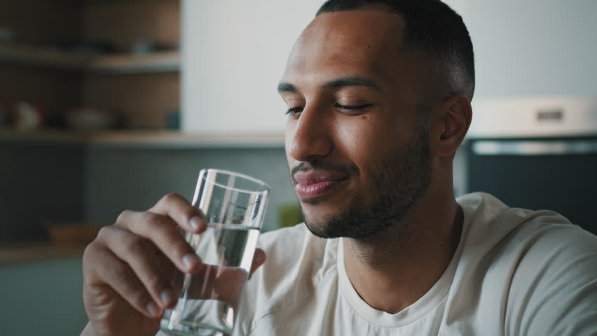 African American healthy sportsman ethnic male guy man athlete sporty trainer indoors drink still cold water with glass drinking refreshment fresh nutrition aqua balance body health care weight loss Royalty-Free Stock Footage #1098022587