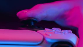 Gamer's hands playing online video game on console TV with joystick, neon color light. Woman presses buttons, using joypad controller, newest wireless gamepad. Hobby, e-sport, macro view