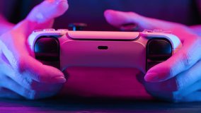Gamer's hands playing online video game on console TV with joystick, neon color light. Woman presses buttons, using joypad controller, newest wireless gamepad. Hobby, e-sport, macro view - Powered by Shutterstock - Get 15% off with code: PIKWIZARD15