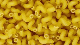 A lot of dry pasta as spirals, rotate circle. Popular Italian and European cuisine. Food background. Top view. Top down food. Vertical video. Close-up.