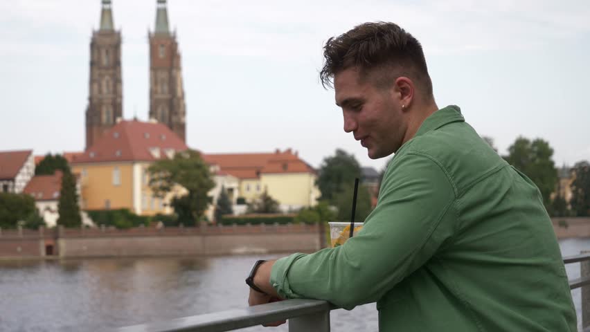 Stylish young man stands near river bank in Wroclaw, Poland