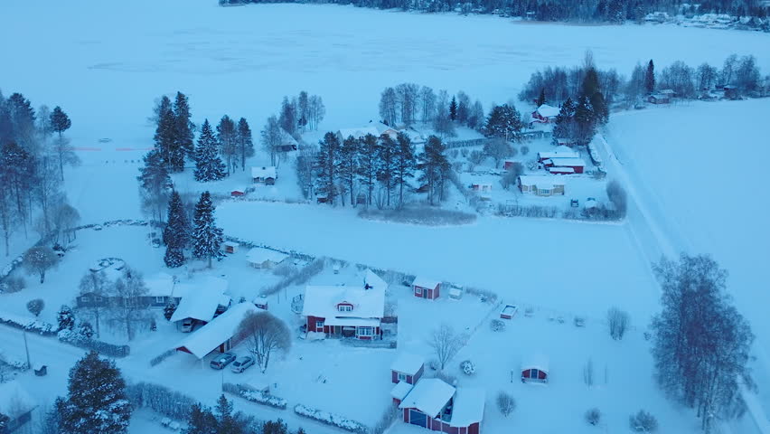 Scenic fly away from Swedish small village, winter snowy landscape - houses, forest, frozen lake