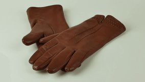Graceful women's brown leather gloves on a white background. A pair of new brown leather gloves isolated on a white background. The concept of clothing for the cold season