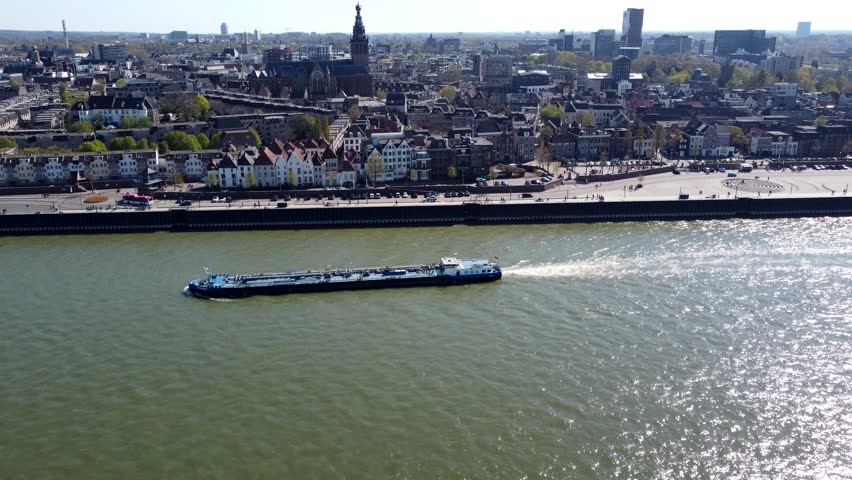 Aerial view of Nijmegen Waal river barge moving over drone flying towards city centre showing cityscape Stevenskerk in background beautiful town located in Gelderland province 4k high resolution Royalty-Free Stock Footage #1098063483