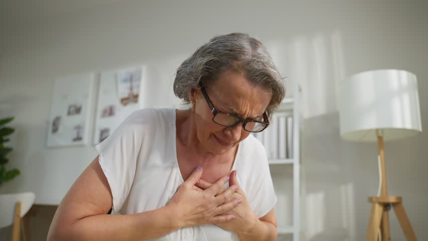 Caucasian senior disabled woman suffer from heart attack on wheelchair. Elder female with chest pain has difficulty breath clutching her chest from acute pain. Hospital Healthcare and medical concept.