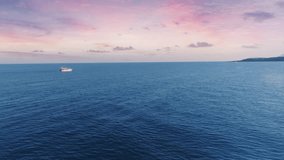 The yacht sails on the sea at sunset. Aerial drone video footage. Blue sea and pink sky. Beautiful clouds. Seascape.