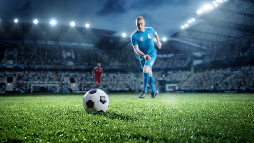 Football World Championship: Soccer Player Runs, Kicks the Ball. Ball Shoots, Grass Sprays Outwards, Full Stadium Crowd Cheers. Camera Moves in Arc Super Slow Motion. Cinematic Shot Captures Victory