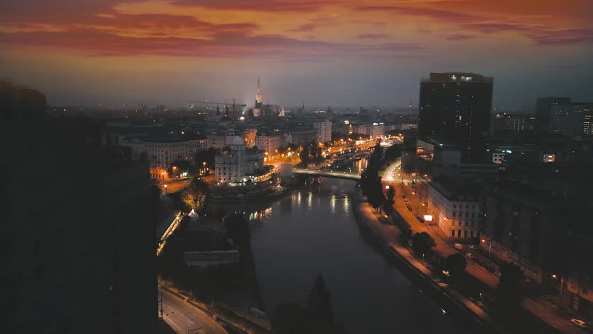 Vienna night skyline drone video in 4K, vienna austria view of city centre fly over river in front of old town vienna cathedral church night view.
