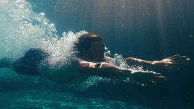 Man dives in the pool. Underwater view of the person diving in the pool and gliding underwater with bubbles - Powered by Shutterstock - Get 15% off with code: PIKWIZARD15