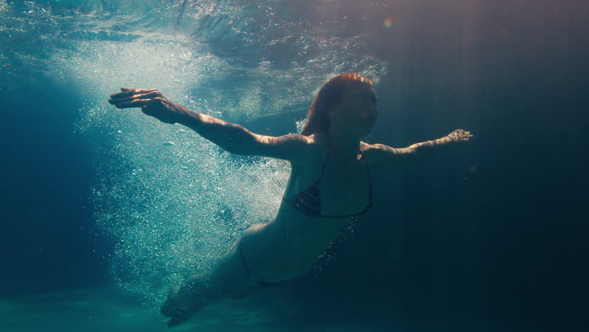 Woman dives in the pool. Underwater view of the girl diving in the pool and gliding underwater with bubbles | Shutterstock HD Video #1098087299