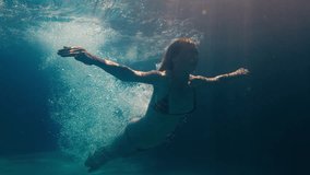 Woman dives in the pool. Underwater view of the girl diving in the pool and gliding underwater with bubbles - Powered by Shutterstock - Get 15% off with code: PIKWIZARD15