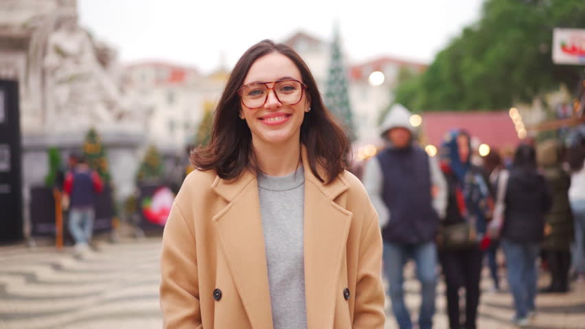 Woman in eyeglasses dressed coat walk city square market looking camera and smile. European female person in glasses walking city warm winter day.  Royalty-Free Stock Footage #1098087361