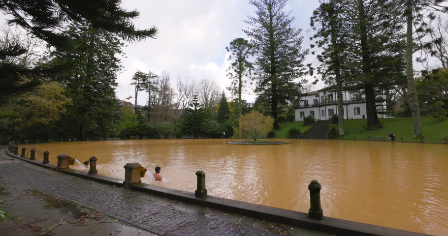 Sao Miguel, Azores, Portugal - December 4. 2022: Orange thermal pool in the Terra Nostra botanical garden at Furnas, Sao Miguel island, Azores, Portugal. The color comes from the oxidated iron.