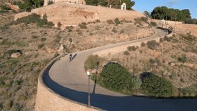 Young fit women athlete on road bicycle climb uphill on serpentine switchback . Snake road Bird eye view. Sport activity motivation video. Spain
