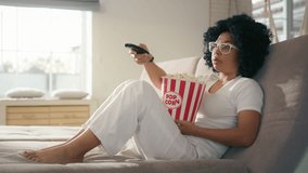 Pretty African American woman in living room using remote control to change channel 4K. Woman of color watching TV for entertainment using remote control. Smiling woman sitting on couch in living.  - Powered by Shutterstock - Get 15% off with code: PIKWIZARD15