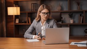 Distance education, english lesson. Young woman in glasses wearing formal suit holding conference call on laptop talks online with group of people studying, working from home, e learning webcam chat.