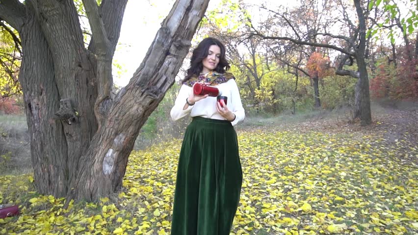Slow Motion attractive woman drinking coffee in autumn forest