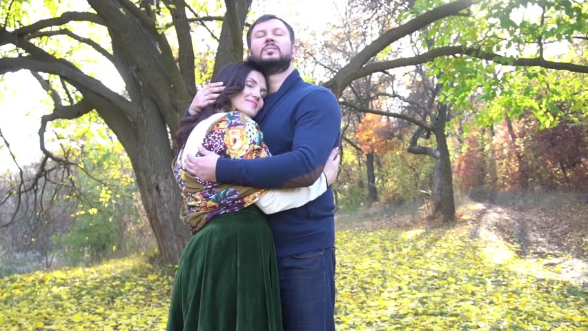 Slow Motion Happy young couple hugs at autumn park alley in evening sunlight