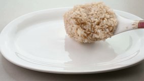 Serving cooked brown rice in a plate.