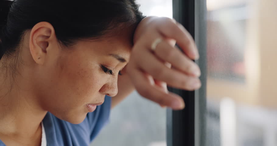 Doctor woman, burnout and anxiety in hospital, workplace and tired in healthcare job, stress or headache. Nurse, sad and exhausted in medical service, clinic or depression in health career by window Royalty-Free Stock Footage #1098105521