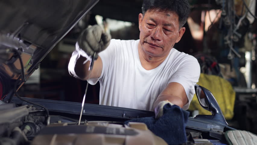 Senior asian male auto mechanic worker checking oil level in car engine at Car Service station. Car maintenance and auto service garage concept. Royalty-Free Stock Footage #1098109313