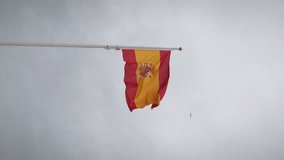 Flag of Spain waving on flagpole against cloudy sky, vertical video. Spanish national flag waving in wind