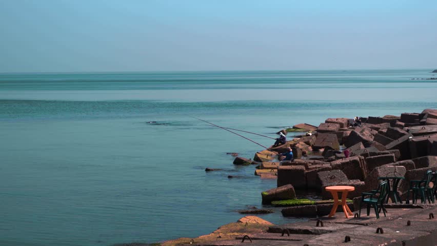 A scenic footage of fishermen hunting with fishing rode on the shore in Alexandria, Egypt