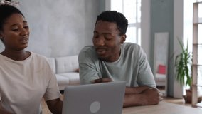 A happy young family is sitting in a cozy living room with a laptop, a positive man helps his woman figure out the problem. - Powered by Shutterstock - Get 15% off with code: PIKWIZARD15