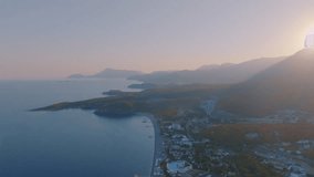 Aerial drone video footage of a tourist town by the sea. Sunset against the backdrop of a mountain landscape. 