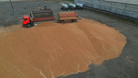 Aerial view of tuck trailer unloading grain at agricultural storage.