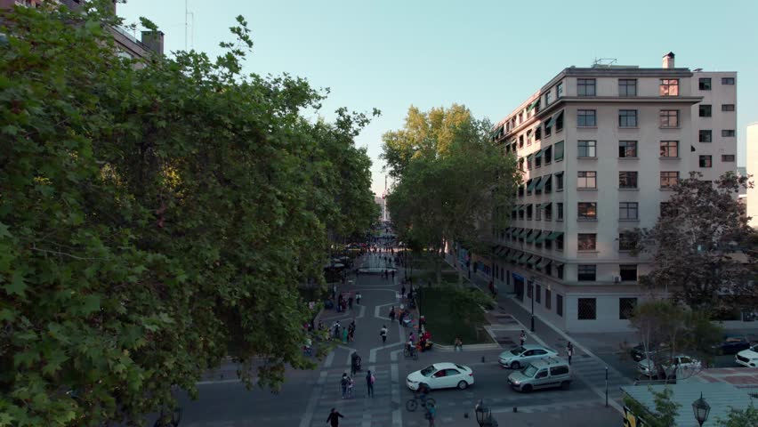 Aerial view boom up among the trees of Paseo Bulnes in Santiago, Chile. Chilean flag in the background