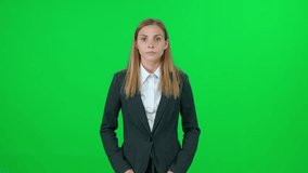 Young woman news reporter stands and speaks on a green background, looks into the camera, template for TV news agencies, female journalist at work, chromakey.