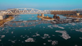 Steel truss iron railway bridge spanning frozen river with floating ice floes during cold foggy winter. Beautiful snowy landscape in cold times. Concept of nature ecology preserving - Powered by Shutterstock - Get 15% off with code: PIKWIZARD15