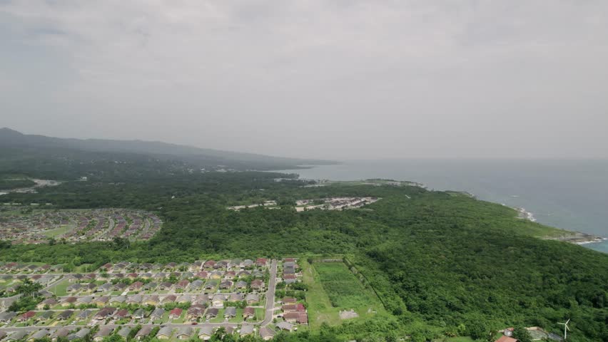 Aerial View of Ocho Rios, Jamaica, Buildings and Green Rainforest by Caribbean Sea Coastline, Drone Shot