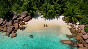Couple on the beach of Anse Lazio beach at Praslin island Seychelles, Secret small beach in the bay of Anse Petite Lazio beach, Praslin, Seychelles - Powered by Shutterstock - Get 15% off with code: PIKWIZARD15