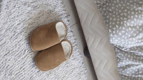 Vertical video, close-up. A woman gets out of bed, inserts her feet into warm slippers.