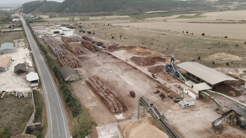 Drone flying over storage of tree trunks in wood processing plant at rural area on a cloudy day 