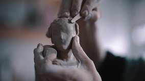 Close-up of the process of creating the clay figure of woman's face. Sculptor modelling sculpture, adding wet clay on the plaster head, adjusting face and hair details in crafts potting workshop. - Powered by Shutterstock - Get 15% off with code: PIKWIZARD15