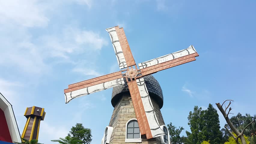 Windmill farmhouse with slowly rotating blades or propellers. A clear blue sky in background. | Shutterstock HD Video #1098178239