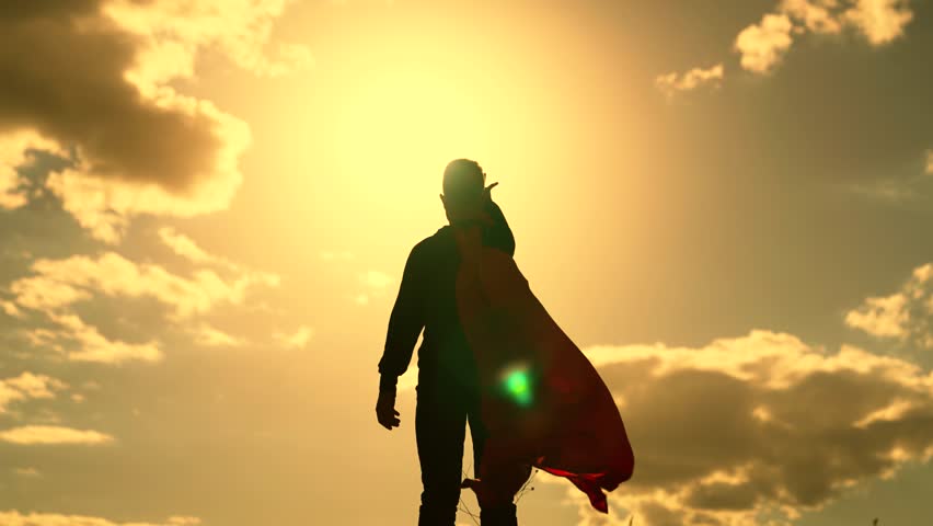Happy kid playing superhero stretches his hand to sky. Childhood dreams, boy playing superhero in red cape childhood dream. Little hero in red raincoat is watching sunset. Child-winner plays in nature Royalty-Free Stock Footage #1098188341