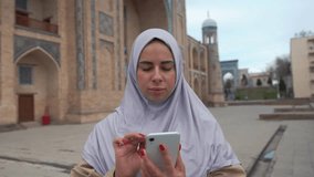 Portrait of young muslim woman wearing hijab using smartphone 