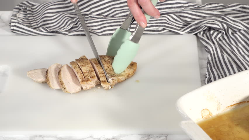 Step by step. Slicing freshly baked chicken breast on a white cutting board. Royalty-Free Stock Footage #1098191393