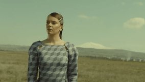 Portrait of lonely woman walking in slow motion through a field . Young stylish lonely girl walking on meadow field. Long skirt fabric flowing by wind . Fashion style. Shot on ARRI Alexa Cinema Camera