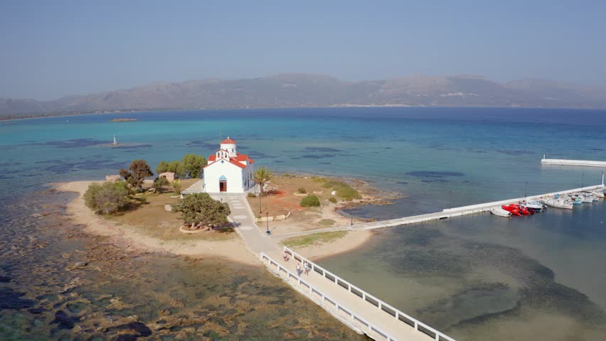 4k drone flight down footage (Ultra High Definition) of Saint Spiridon church in Elafonisos port. Stunning morning seascape of Mediterranean Sea, Elafonisos island, Greece, Europe.