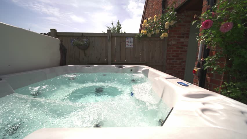 Slow wide side to side shot of private hot tub jacuzzi at vacation rental in summer, Royalty-Free Stock Footage #1098195649